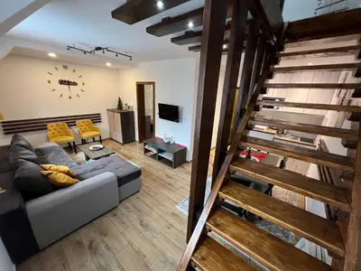 a living room with a couch and a staircase at Apartmani Vidatela Kopaonik in Kopaonik