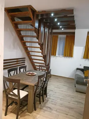 a dining room with a table and chairs and a staircase at Apartmani Vidatela Kopaonik in Kopaonik