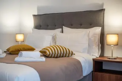 a bedroom with a large white bed with two lamps at Apartman EROS in Vrnjačka Banja