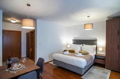 a bedroom with a bed and a table and a dining room at Apartman EROS in Vrnjačka Banja