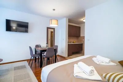 a bedroom with two beds and a table with chairs at Apartman EROS in Vrnjačka Banja