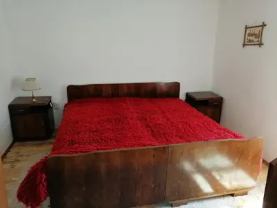 a bedroom with a wooden bed with a red blanket at Etno kuca Nikolov in Dimitrovgrad