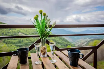 a wooden table with two glasses and a vase with flowers at Apartments View Dvori E25 in Kopaonik