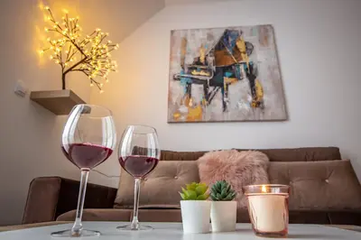 two wine glasses on a table with a couch at Apartments View Dvori E25 in Kopaonik