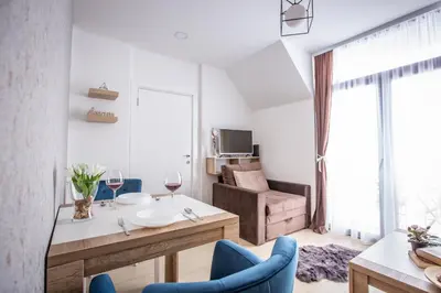 a living room with a table and blue chairs at Apartments View Dvori E25 in Kopaonik