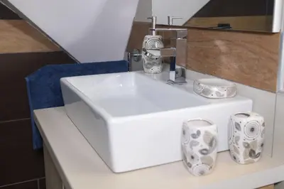 a bathroom with a sink and two cups on a counter at Apartman Milmari Idila in Kopaonik