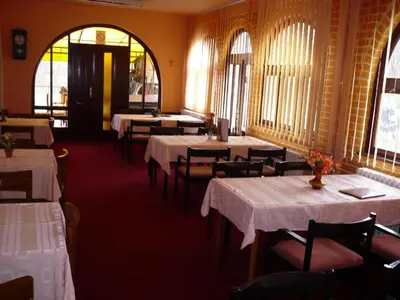 a dining room with white tables and chairs and windows at Motel Stara Vrba in Kuršumlija