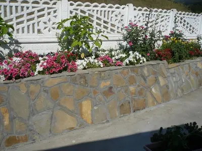 a retaining wall with flowers in front of a white fence at Motel Stara Vrba in Kuršumlija
