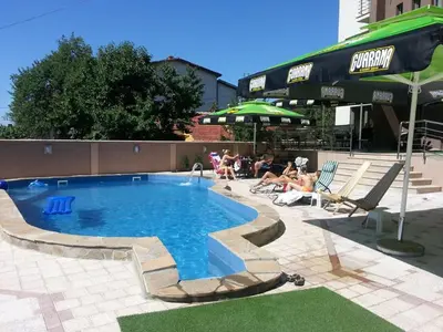 a swimming pool with people sitting in chairs around it at Guesthouse Vila DND in Niška Banja