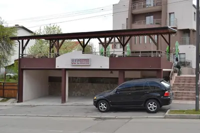 a black car parked in front of a building at Guesthouse Vila DND in Niška Banja