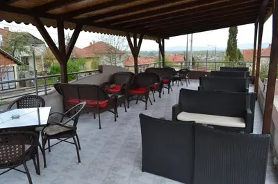a row of chairs and tables and chairs on a patio at Guesthouse Vila DND in Niška Banja
