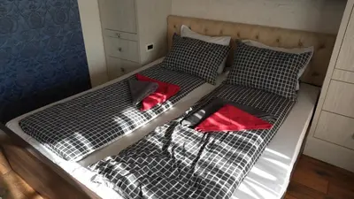 two beds with black and white sheets and red pillows at Bella studios in Kruševac