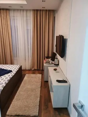 a room with a bed and a table and a tv at Bella studios in Kruševac