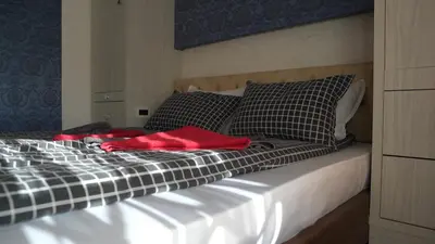 a bed with a red blanket and pillows on it at Bella studios in Kruševac