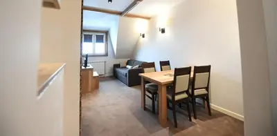 a dining room with a table and chairs and a couch at Lonka apartman Kopaonik in Kopaonik