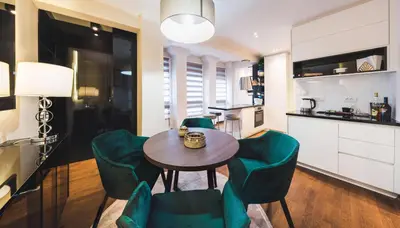 a kitchen and dining room with a table and green chairs at Majestic Apartment in Jagodina