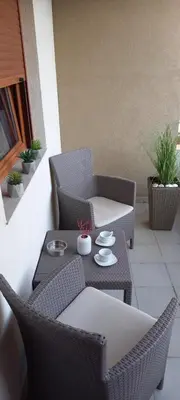 a patio with two wicker chairs and a table at Apartman DiamondLux Vrnjacka Banja in Vrnjačka Banja