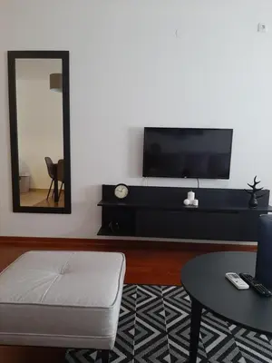 a living room with a tv and a table and a mirror at Apartman DiamondLux Vrnjacka Banja in Vrnjačka Banja