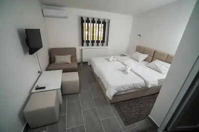 a bedroom with a bed and a couch and a television at Prenociste ADRIA in Vranje