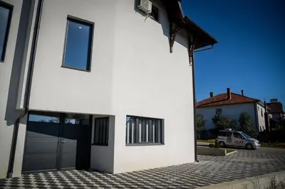 a white house with a car parked in front of it at Prenociste ADRIA in Vranje