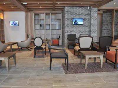 a living room with chairs and tables and a wall at The Nest Apartman, Župa Wellness & Spa Kopaonik in Kopaonik