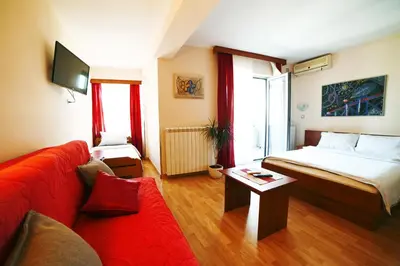 a hotel room with a bed and a red couch at Dental apartman in Vrnjačka Banja