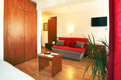a living room with a red couch and a table at Dental apartman in Vrnjačka Banja