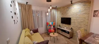a living room with a couch and a tv on a brick wall at Hedonic in Kopaonik