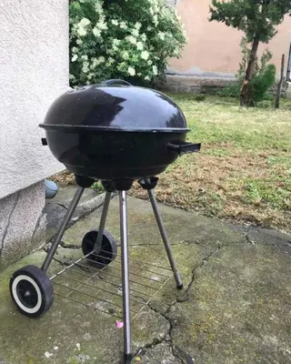 a grill sitting on a stand next to a house at Vila Milica in Kraljevo