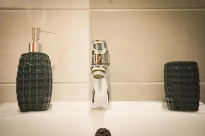 a bathroom sink with a faucet and two soap dispensers at Apartman La Casa Di Elena in Vrnjačka Banja