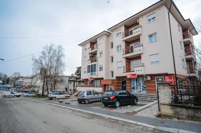 a building with cars parked in a parking lot at Apartman La Casa Di Elena in Vrnjačka Banja