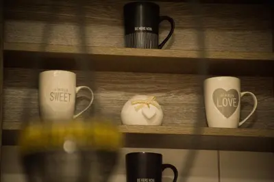 a shelf with coffee mugs and a glass of wine at Apartman La Casa Di Elena in Vrnjačka Banja