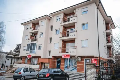a building with cars parked in front of it at Apartman La Casa Di Elena in Vrnjačka Banja