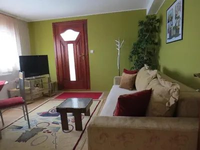a living room with a couch and a table and a door at Apartman Bilja in Vrnjačka Banja