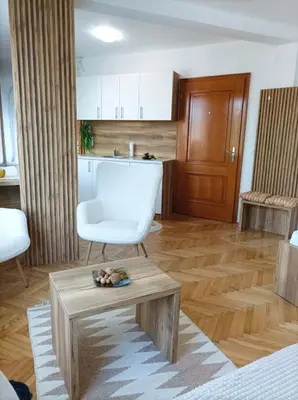 a living room with a white chair and a table at Apartman Rajska Banja in Vrnjačka Banja