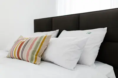 a bed with white pillows and a black headboard at Apartmani Veselinović in Vrnjačka Banja