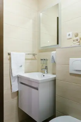 a white bathroom with a sink and a mirror at Apartmani Veselinović in Vrnjačka Banja