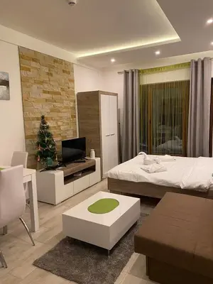 a bedroom with a bed and a living room with a christmas tree at MILMARI APARTMAN P03 in Kopaonik