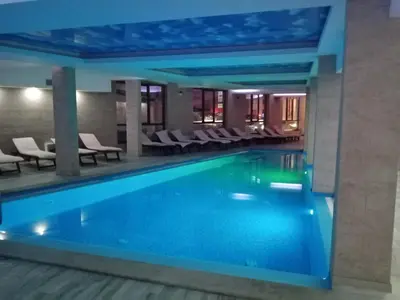 a swimming pool in a hotel lobby with chairs at MILMARI APARTMAN P03 in Kopaonik
