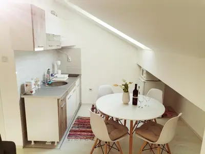 a small white kitchen with a table and chairs at Apartman ST.Nedeljkovic Sokobanja in Soko Banja