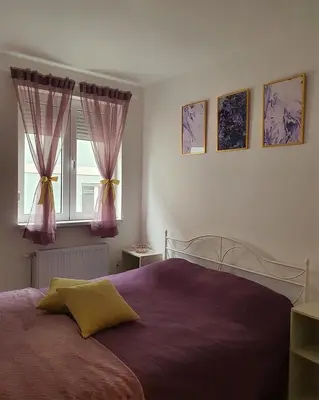 a bedroom with a bed with purple sheets and a window at LILAC Apartment in Vrnjačka Banja