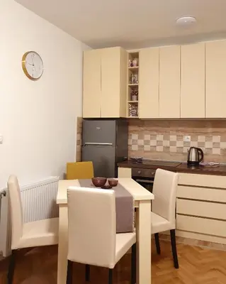 a kitchen with a table and chairs and a clock on the wall at LILAC Apartment in Vrnjačka Banja