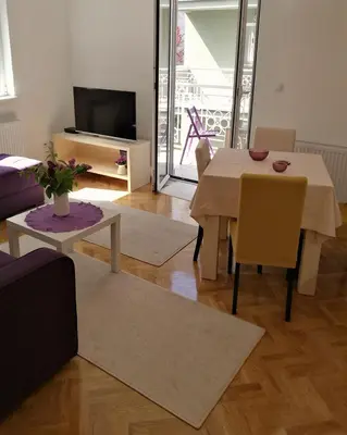 a living room with a table and chairs and a television at LILAC Apartment in Vrnjačka Banja