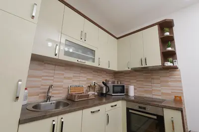a kitchen with white cabinets and a sink at Capitol Apartmani in Vrnjačka Banja