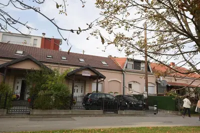 a woman walks past a house at Capitol Apartmani in Vrnjačka Banja