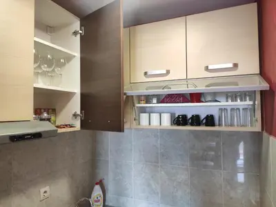 a kitchen with wooden cabinets with shoes on the shelves at Modern cozy apartment in Niš