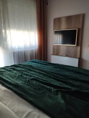 a bedroom with a green bed with a flat screen tv at Studio City day in Jagodina