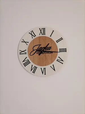 a clock with a wooden circle on a white background at Apartman Jasna in Vrnjci