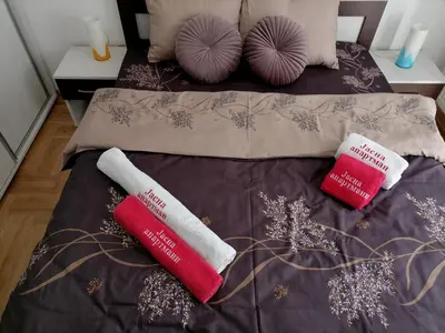 a bed with two red and white pillows on it at Apartman Jasna in Vrnjci