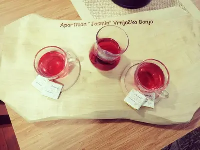 two glasses of red wine sitting on a cutting board at Apartman Jasmin in Vrnjačka Banja